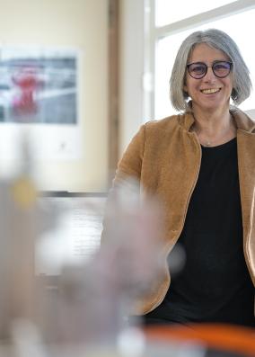 Christèle est appuyée contre son bureau en souriant